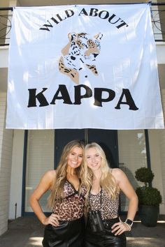 two beautiful young women standing next to each other in front of a white sign that says wild about kappa