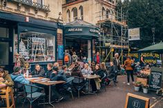 people are sitting at tables outside in front of shops