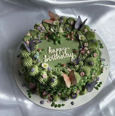 a green birthday cake decorated with flowers and butterflies