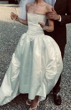 a man and woman dressed in wedding attire posing for the camera with wine glasses on their feet