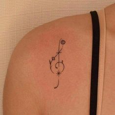 the back of a woman's shoulder with a small flower tattoo on her left arm