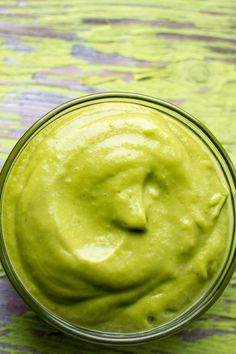 a glass bowl filled with green guacamole on top of a wooden table