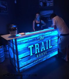 a man and woman standing at the front desk of a bar with blue lights on it