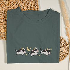 Cow Over the Moon Embroidered Shirt Add a whimsical touch to your wardrobe with our Cow Over the Moon Embroidered Shirt. Perfect for animal lovers and farm enthusiasts, this shirt combines humor and charm in a delightful design. Design: This shirt features an intricately embroidered cow leaping over the moon, capturing a playful and imaginative scene. The detailed stitching of the cow and moon makes this shirt a standout piece, bringing a smile to anyone who sees it. Material: Crafted from high- Cow And Moon, Cow Graphic Tee, White Cotton T-shirt With Moon Print, Cow Print Cotton Short Sleeve T-shirt, Cotton Short Sleeve T-shirt With Cow Print, Casual Cotton T-shirt With Moon Print, Cow Tshirt, Cozy Fits, Embroidered Shirt