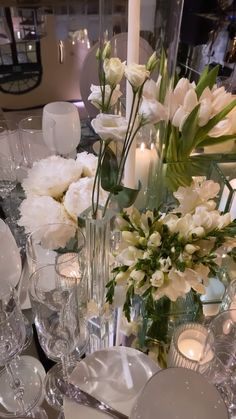 a table is set with white flowers and candles for an elegant dinner or party setting