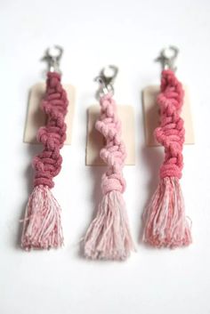 three pink and white tasselled keychains sitting on top of each other