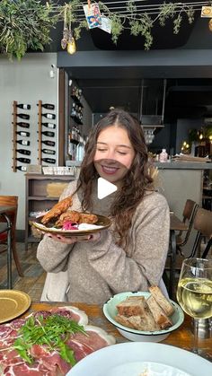 a woman sitting at a table with plates of food