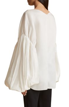 An oversized silhouette accentuated with dropped shoulders and voluminous pleated sleeves defines this modern take on a peasant top crafted of silk gazar. 30" length (size 8) Bateau neck Dropped shoulders Long sleeves 100% silk Dry clean Made in the USA of imported fabric Designer Clothing Evening Tops With Gathered Balloon Sleeves, Formal Silk Blouse With Draped Sleeves, Elegant Blouse With Voluminous Blouson Sleeves, Chic Puff Sleeve Top With Bishop Pleated Sleeves, Evening Silk Blouse With Gathered Sleeves, Silk Blouse With Gathered Sleeves For Evening, Elegant Formal Blouse With Elastic Sleeves, Elegant Tops With Blouson Sleeves, Elegant Tops With Gathered Voluminous Sleeves