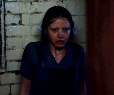 a woman standing in front of a brick wall with her face covered by white paint