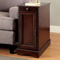 a small wooden cabinet sitting next to a gray chair on a hard wood floor in a living room