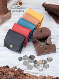 several different colored leather wallets next to some coins