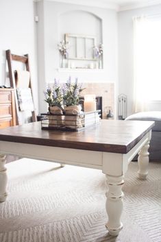 a living room with a coffee table in the middle and flowers on top of it