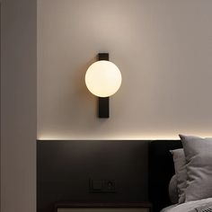 a bed with pillows and a light on the wall