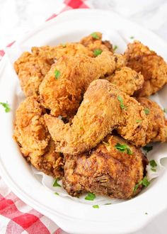 fried chicken in a white bowl on a red and white checkered tablecloth with parsley