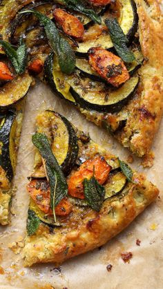 a pizza with zucchini, squash and spinach is cut into four slices