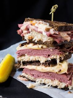 there is a sandwich with meat and cheese on it next to a slice of lemon