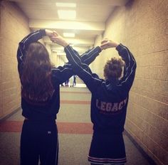 two young women standing in a hallway holding their hands up to each other's shoulders