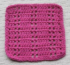 a pink crocheted square sitting on top of a white blanket