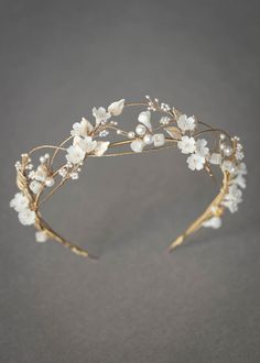 a headband with white flowers and leaves on the side, sitting on a gray surface