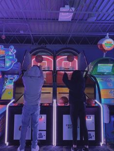 two people standing next to each other in front of some arcade machines with neon lights