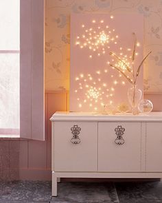 a white dresser sitting next to a window in a room with pink walls and wallpaper