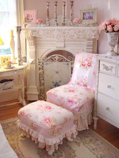 a pink chair and ottoman in front of a white fireplace with flowers on the mantle