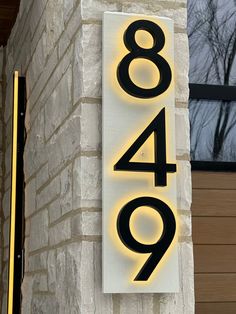 a house number sign on the side of a brick building with lights around it and trees in the background