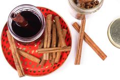 cinnamon sticks on a red plate next to a jar of liquid and some cinnamons