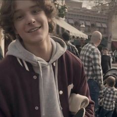 a young man standing in front of a crowd of people wearing hoodies and sweatshirts