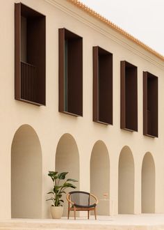 a chair sitting in front of a building with arched windows and shutters on the side