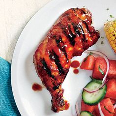 a white plate topped with meat and veggies next to a corn on the cob