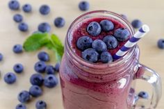 a glass with some blueberries in it next to a bowl of minty greens