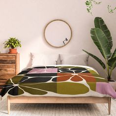 a bed in a room with a plant on the wall and a round mirror above it