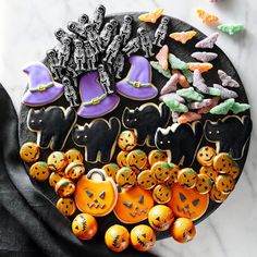 decorated cookies are arranged on a plate with halloween decorations in the shape of pumpkins