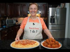 a woman in an orange shirt is holding two plates with spaghetti and meatballs on them