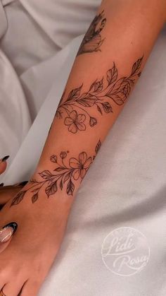 a woman's foot with flowers and leaves tattooed on her left leg, while laying in bed