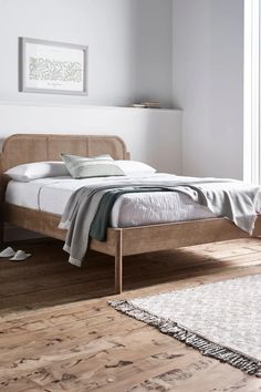 a bed sitting on top of a wooden floor next to a white rug and window