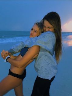 two women hugging each other on the beach