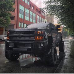 a large black truck parked on the side of a road next to a tall building