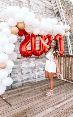 a woman standing on a porch with balloons in front of her and the word boos spelled out