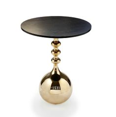 a table with a black top and two gold balls on the bottom, sitting in front of a white background