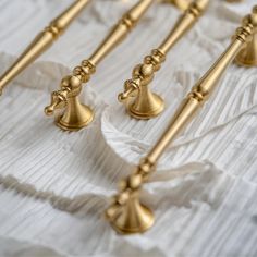 four golden candlesticks are lined up on a white table cloth with gold handles