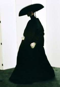 a woman in a long black dress and large hat