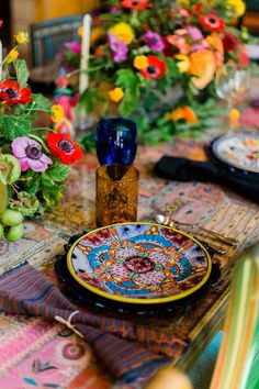 the table is set with colorful plates and flowers