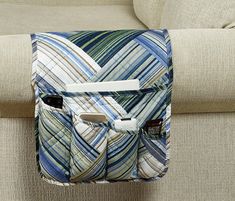 a blue and white bag sitting on top of a couch next to a beige chair