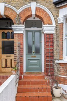 a green door is on the side of a brick building with white trim and arched windows