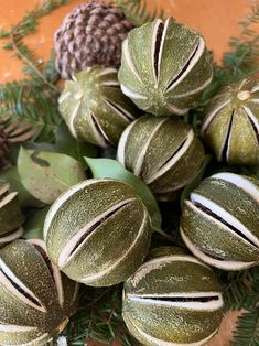 some green and white ornaments sitting on top of a wooden table next to pine cones