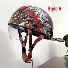 a motorcycle helmet with feathers on it sitting next to a potted plant and other items