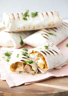 two burritos sitting on top of a wooden cutting board