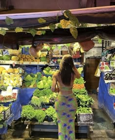 a woman standing in front of a fruit and vegetable stand